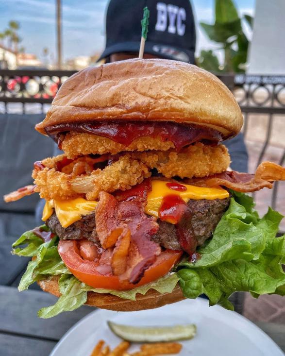 Wild West Burger · Applewood smoked bacon, onion rings, BBQ sauce, cheddar cheese. lettuce, tomato and mayo. Served on a grilled brioche bun with a pickle.