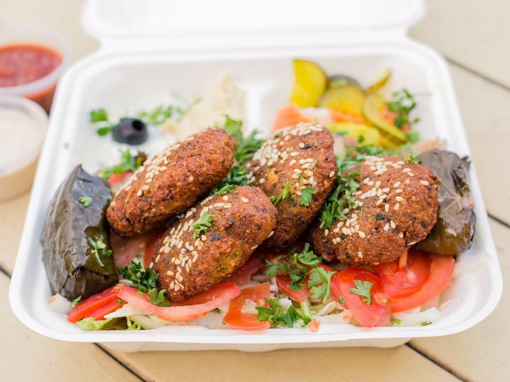 Taamiya Platter · Egyptian falafel. Lettuce, onions, tomatoes, marinated eggplant, covered with Egyptian falafel balls drizzled with tahini sauce. Pickled vegetables, tzatziki sauce, hummus and 2 dolmas on the side.