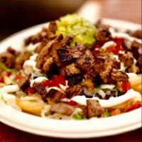 Asada/Beef Nachos · Beef Nachos topped with beans, onions, tomatoes, cilantro, sour cream, queso fresco, and avo...