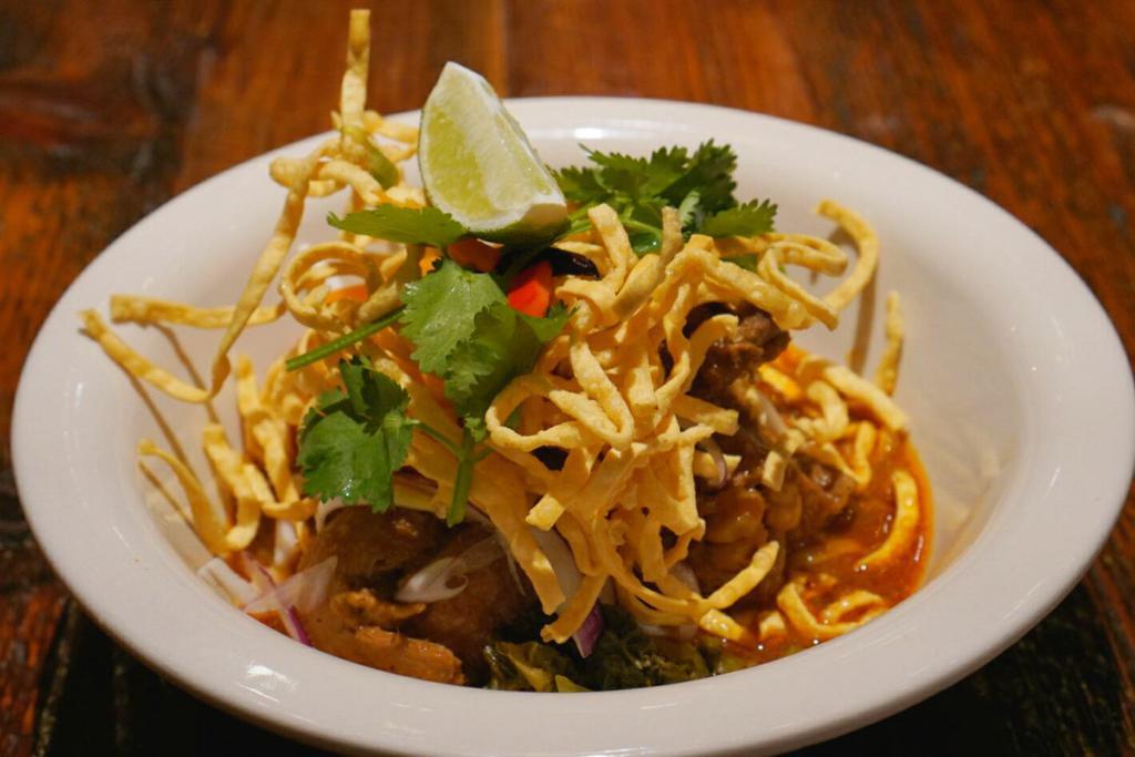 Khao Soy (Noodle Curry) · Braised Chicken thigh, Egg noodle, Beanspout, Pickled mustard green, Red onion and Topped with Crispy noodle. Spicy (Northern-Style Noodle Curry)