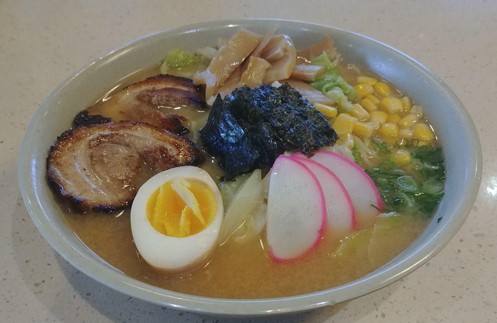 Miso Ramen · Ramen noodles in miso-based broth with 2 pieces chashu (BBQ pork), fish cake, bamboo, half hard-boiled egg, corn, cabbage, seaweed, and green onions. Served with salad.