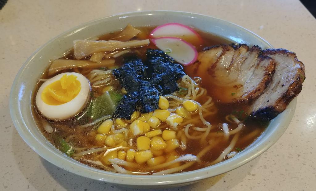 Shoyu Ramen · Ramen noodles in soy-based broth with 2 pieces chashu (BBQ pork), fish cake, bamboo, half hard-boiled egg, corn, cabbage, seaweed, and green onions. Served with salad.
