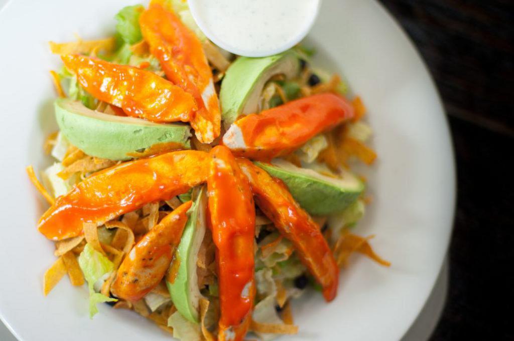 Buffalo Chicken Salad · A bed of romaine topped with black beans, shredded cheddar cheese, avocado, tortilla strips, and Buffalo tossed grilled chicken served with ranch dressing.