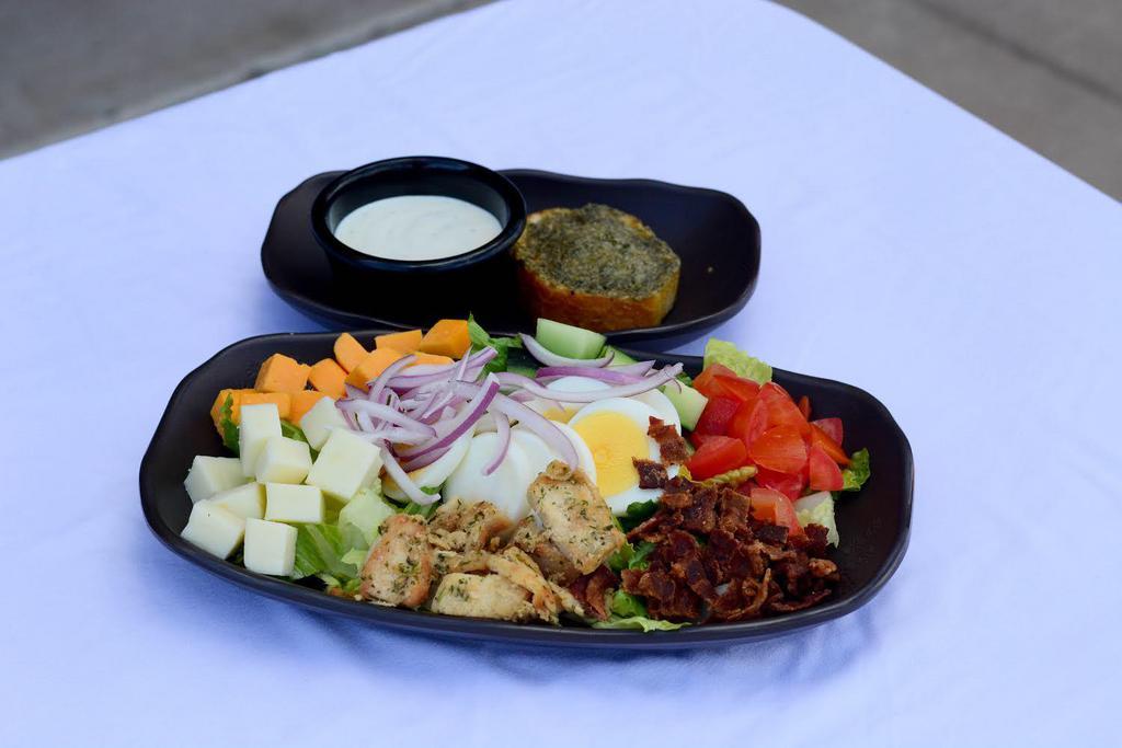 Cobb Salad · Grilled chicken breast, bacon, hard-boiled egg, cheddar, mozzarella, blue cheese, romaine, tomato, cucumber, red onion, garlic bread, choice of dressing (on the side).