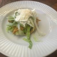 Tostada · Fried corn tortilla, black beans spread, shredded lettuce, Mexican cream and cotija cheese.