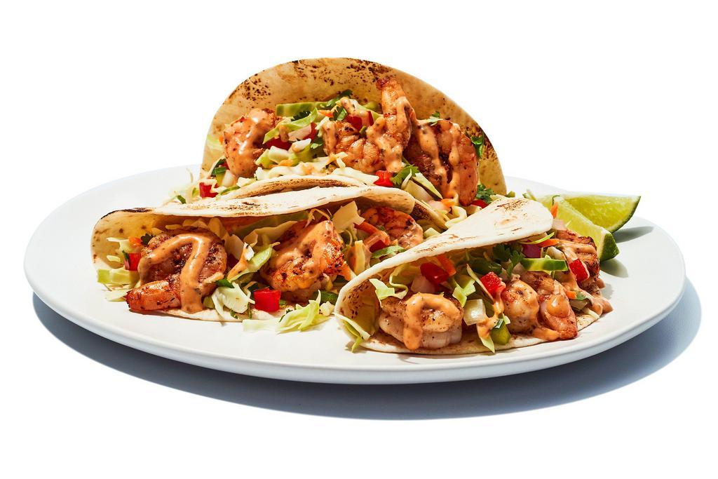 Baja Shrimp Tacos · We grill seasoned shrimp, then wrap them in flour tortillas with an un-shrimp amount of cabbage, pico de gallo and special sauce. Welcome to flavor beach.