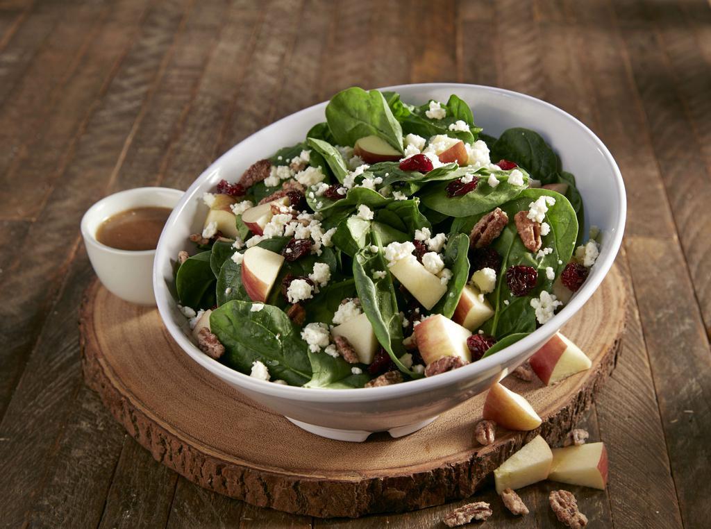 Enlightened Spinach Salad · Fresh spinach topped with dried cherries, apples, feta cheese and homemade candied pecans.