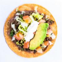 Tostada · Beans, onion, cilantro, lettuce, tomato, sour cream, and avocado. Showered with hot sauce.