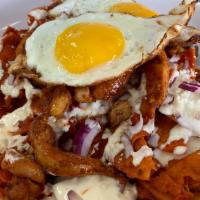 Chilaquiles Rojos · House-made tortilla chips tossed in a red chile sauce topped with diced onion, sour cream, q...