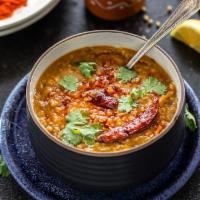 Tarka Daal · ‘Masoor Daal’ cooked with turmeric, tomatoes onions and topped with roasted garlic.
