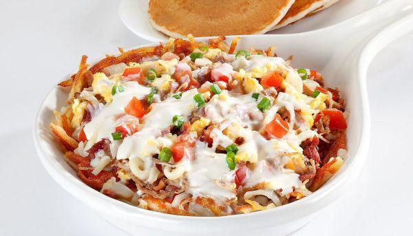 Carnitas Queso Skillet · Two scrambled eggs, pulled pork, bacon, sausage, tomatoes, onions, on a bed of seasones hash browns, topped with jack cheese, whate queso, green onions.