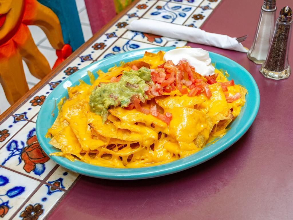 Super Nachos · Chips, beans, choice of chicken, ground beef, or chorizo, topped with cheddar cheese, guacamole, sour cream, onions, and tomatoes.