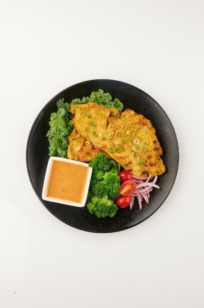 Satay Chicken Steak · Grilled herb-marinated chicken served with kale, broccoli, peanut sauce, and rice on side.