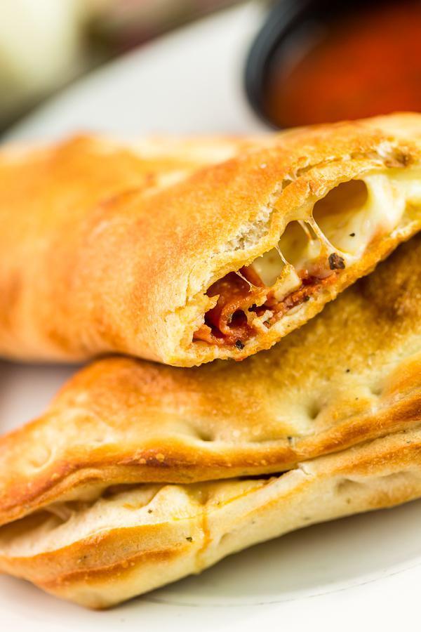 Chicken Pine Nut Calzone · Olive oil, roasted garlic, roasted chicken, pine nuts, spinach, Chevre Goat cheese and Mozzarella. Served with a side of Pasquini family recipe pizza sauce.