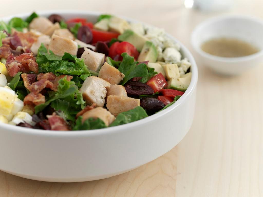 Classic Cobb Salad · A blend of greens topped with diced grilled chicken, avocado, hard-cooked eggs, applewood-smoked bacon, Kalamata olives, tomatoes, and bleu cheese crumbles served with our herbed vinaigrette on the side. Gluten free.