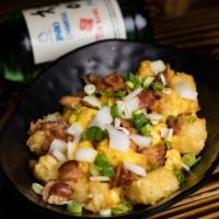 Tater Tots · Crispy tater tots topped with nacho cheese, onions, green onions, and bacon bits.