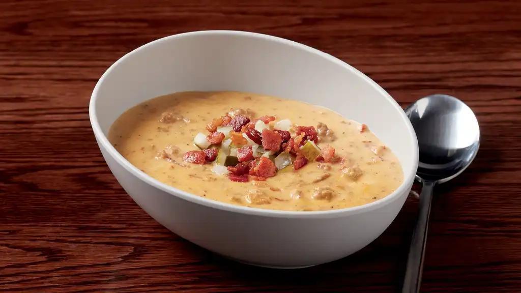 Cheeseburger Chowdah · Fresh ground beef, onions, bacon, potatoes, and government cheese in a creamy soup topped with diced pickles and crispy bacon.  540 calories.