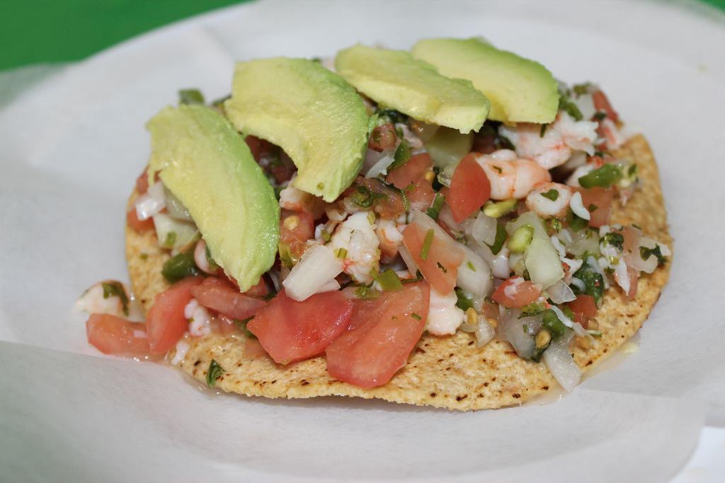 Tostada De Ceviche · Seafood. Tortilla shell with lime, crab, shrimp, onions, tomatoes, cilantro and avocado.