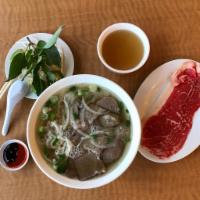 P1. Pho Dac Biet (New York Steak) · Sliced New York steak strip, beef meat balls, brisket and tendon in a rich beef broth with f...