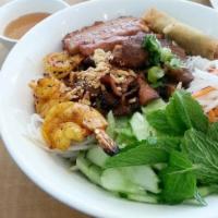 B1. Bun DaC Biet · Contains gluten. Grilled pork egg rolls, pork patty, shrimp with rice noodles on a bed of le...