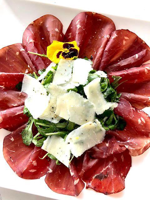 Carpaccio di Bresaola · Cured beef carpaccio, arugula salad with lemon dressing, shaved Parmigiano, bread.