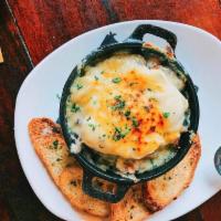 Baked Eggs a la Francaise · Poached eggs nestled in grilled hash browns with sautéed mushrooms and ham, finished with gr...