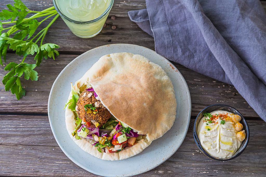 Traditional Falafel Pita · Freshly made falafel in a warm and fluffy pita pocket. Comes with hummus, tomato cucumber mix, mixed greens, diced pickles, fresh mint and tahini sauce.