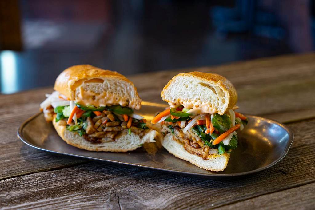 Pork Belly Banh Mi · Roasted pork belly, pickled veggies, diced cucumbers, cilantro, jalapenos, Sriracha mayo and soy glaze on a toasted baguette.
