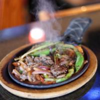 Fajitas · Hot sizzling plate prepared with peppers, tomatoes and onions, served with a side of sour cr...