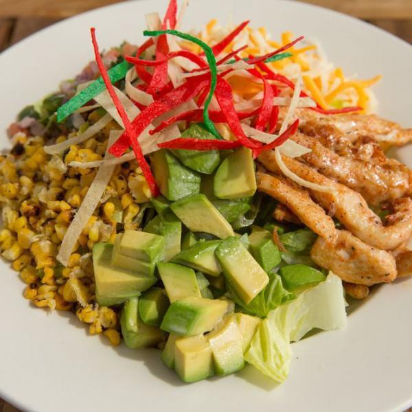 Mexi-Cobb Salad · Heritage lettuce tossed in onion thyme vinaigrette and topped with marinated chicken strips, pico de gallo, cheese blend, corn, cucumbers, avocado and tortilla strips.