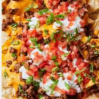 BEEF NACHO SUPREME · Ground beef , Pico Degallo,  sour cream, guacamole and mixed cheese served on house made tor...