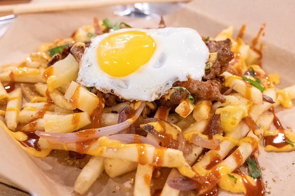 Nom Fries · Our version of loaded fries, comes with fries, grilled onions, pineapples, your choice of protein, drizzled with gochujang sauce and fire cracker, topped with a sunny side up egg, sprinkled with cilantro