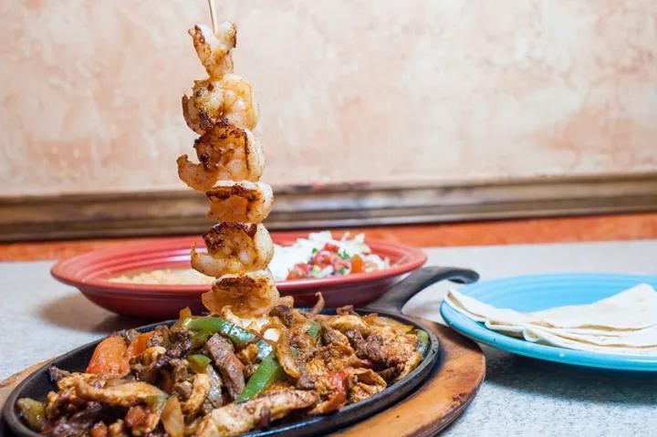 Parrillada Fajitas · Steak, chicken, shrimp, sausage and carnitas with grilled onions, bell peppers and tomatoes. Served with rice, beans, lettuce, pico de gallo, guacamole and sour cream.