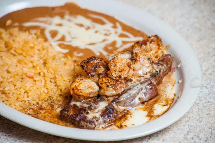 Steak Vallarta · 12 oz. rib-eye steak topped with shrimp and nacho cheese. Served with rice, beans, guacamole salad and flour tortillas.