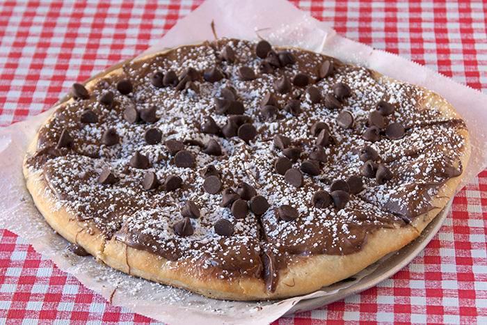 Nutty Pizzetta · Chocolate hazelnut Nutella pizza topped with chocolate chips and powdered sugar.