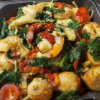 Shrimp & Scallops · Sautéed in a garlic wine sauce with artichokes, spinach,  sundried & fresh tomatoes over lin...