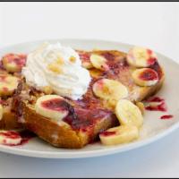 Banana Berry French Toast · Our Thick Griddled French Toast topped with bananas, homemade berry sauce, tres leches, stre...