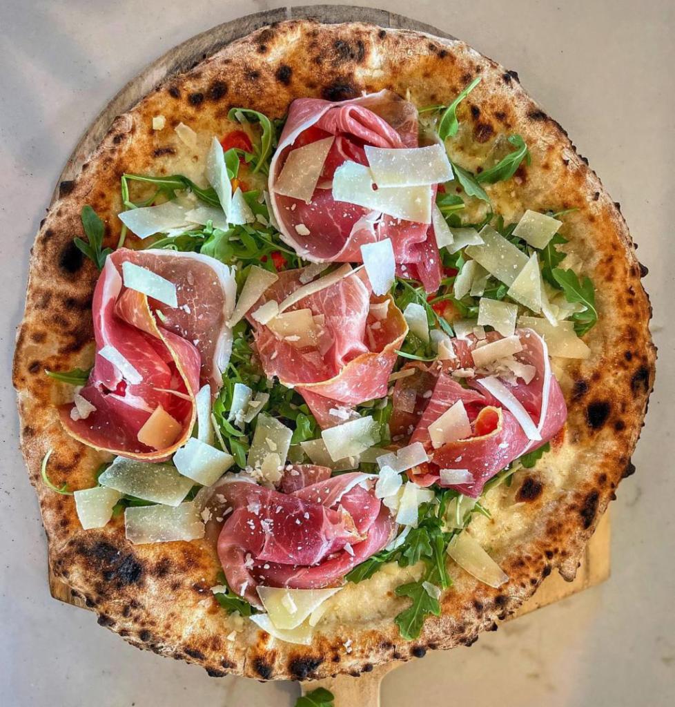 Bufalina Pizza · White pizza with grape tomatoes, basil, mozzarella, arugula, prosciutto and shaved Parmigiano. 