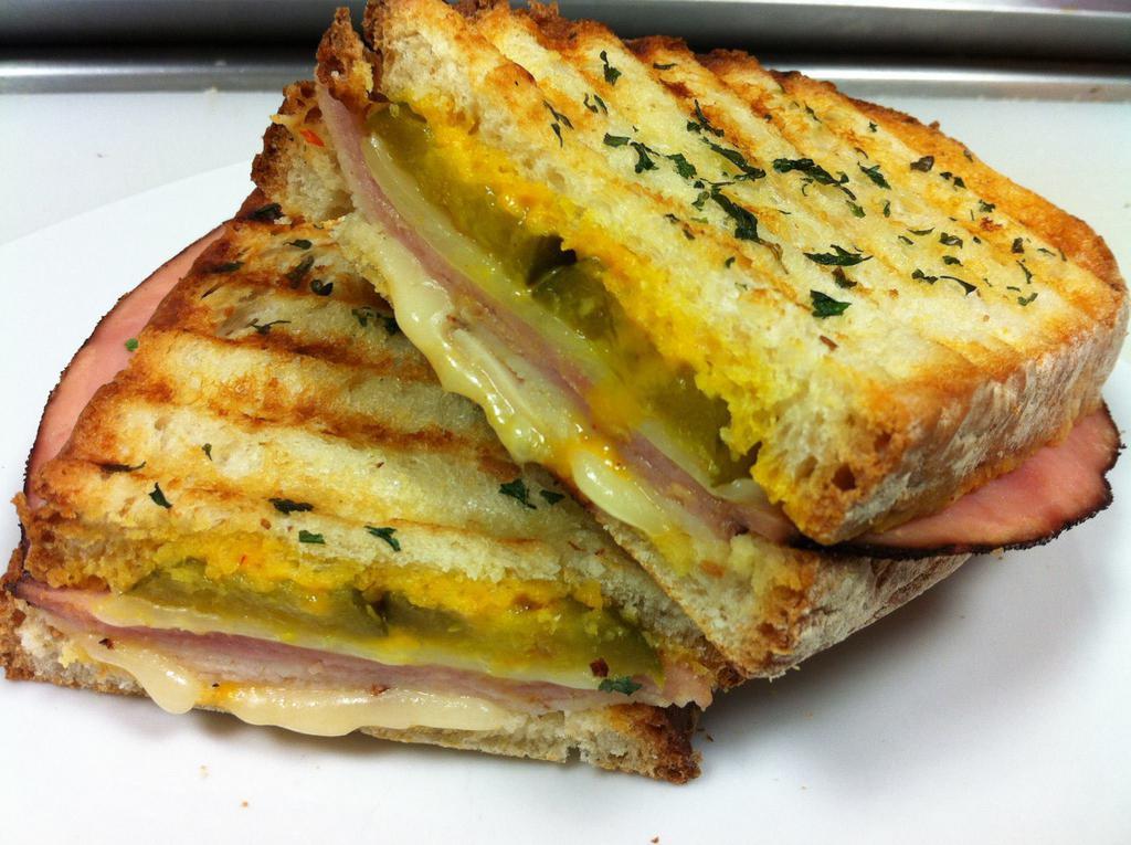 Cuban Panini  · Roasted chicken, black forest ham, baby swiss, bread and butter pickles, red pepper mustard spread. Served on hot pressed panini bread with a side of kettle chips.