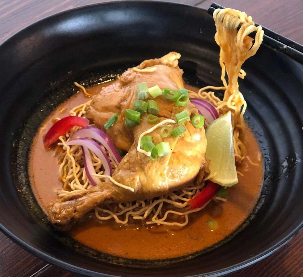 Kao Soy Gai · Chicken legs with egg noodle in special yellow curry soup topped with red and green onions.