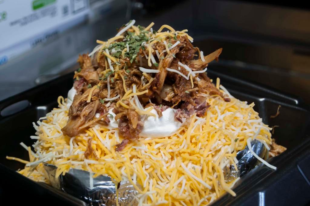 Famous Outlaw Potato · Each potato is over 1 lb. before toppings! Butter, cheese, sour cream, bacon, chives and a heaping pile of meat on top.