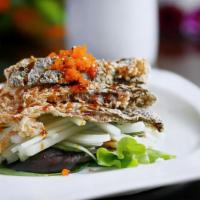 Salmon Skin Salad · Crispy salmon skin beds on sliced cucumber, topped with caviar, scallion, sesame seeds and e...