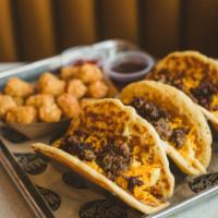 Brunch Pacos · Three buttermilk pancake tacos with scrambled eggs, cheddar cheese and choice of bacon or sa...