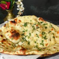 Garlic Naan · Naan bread topped with freshly chopped garlic and cilantro. Topped with butter.