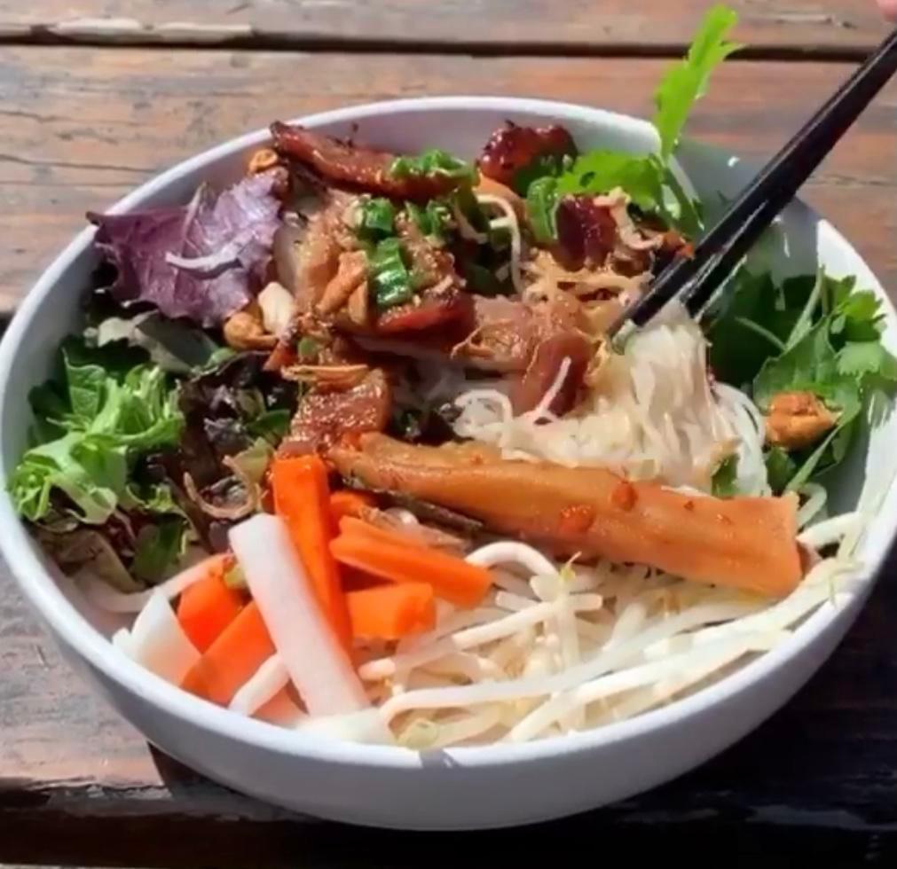 Grilled Pork Vermicelli · Grilled pork, vermicelli rice noodles, lettuce, fresh herbs, cucumber, beansprouts, pickled carrot and daikon, jalapenos, and topped with crushed cashews and crispy shallots. Served with fish sauce and a mung bean and taro egg roll.
