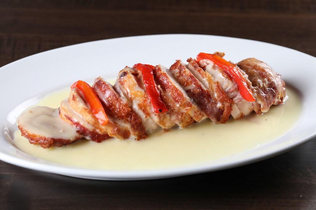 Pollo Rumbero · Chicken breast wrapped with bacon, stuffed with ham and Swiss cheese, and topped with a creamy sauce.