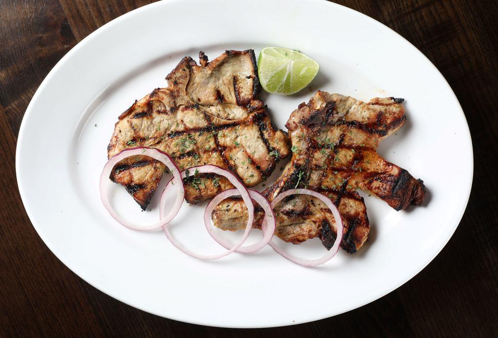 Chuleta a la Parrilla · A pair of pork chops slowly grilled with a splash of fresh lime.