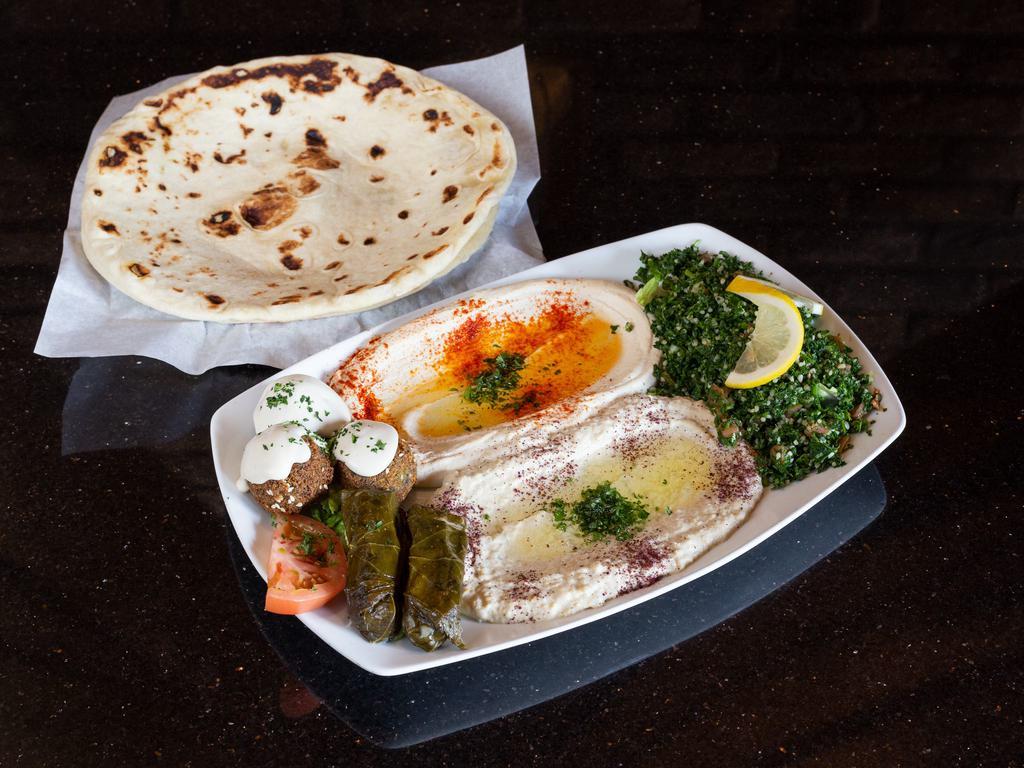 Mezza Plate Sampler · Order of hummus, baba ghanouj, tabouli salad, grape leaves and falafel topped with tahini sauce. Served with fresh baked flatbread. Vegetarian.