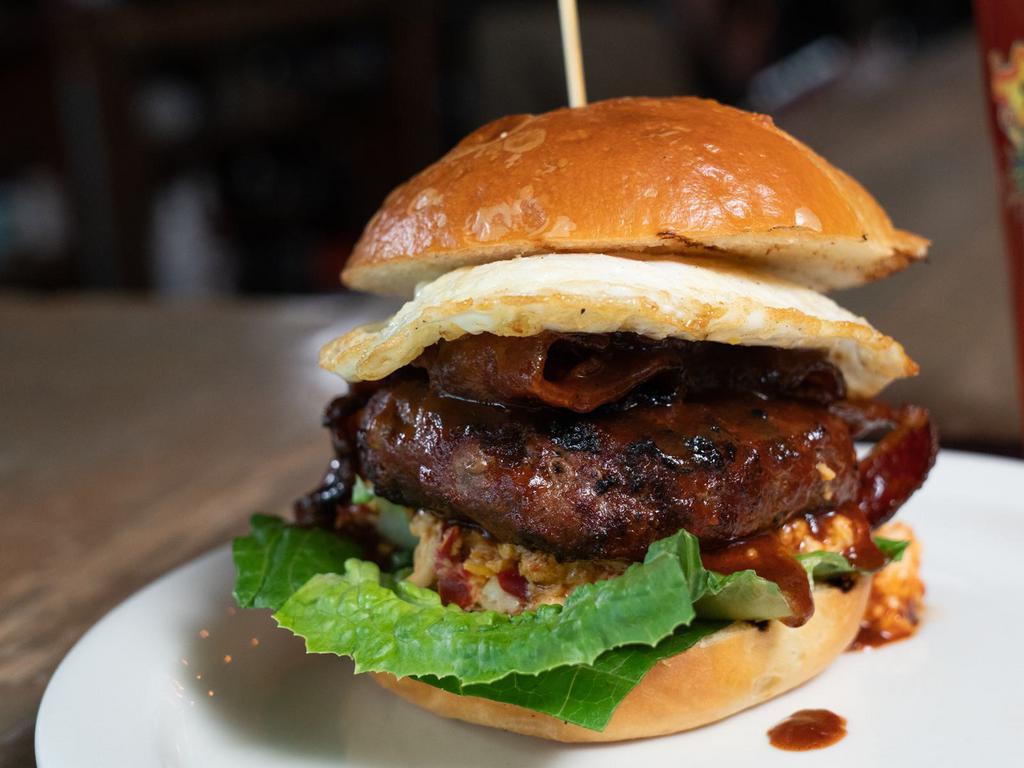 Southern Burger · Seasoned ground beef with pimento cheese, candied bacon, bbq sauce, fried egg, crisp romaine, stacked on a brioche bun. 