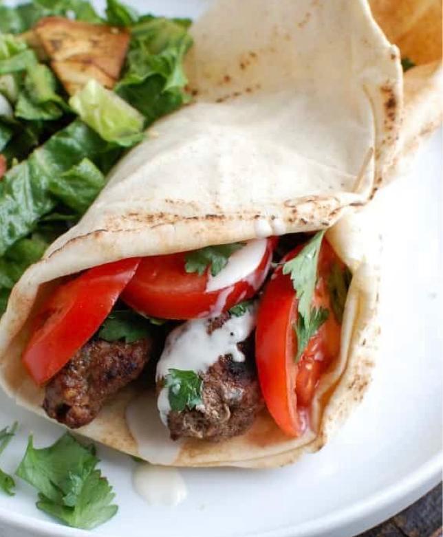 Grilled Beef Kabob Wrap · Marinated beef served with choice of lettuce, tomatoes, onions, pickles, hummus, tahini, tzatziki, feta, tabouli, cucumbers, and banana peppers in a wrap. 